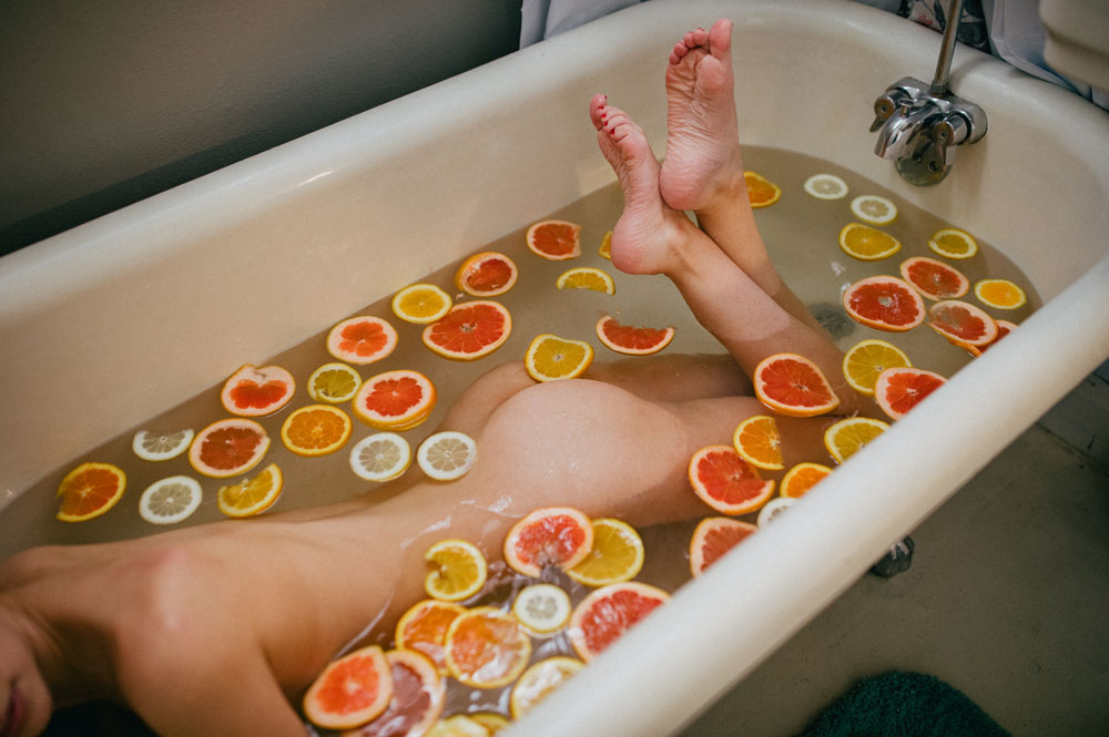nude woman in bath with lemons and oranges